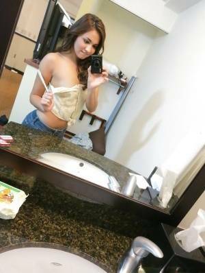 Sassy brunette stripping in front of the mirror and making selfies on fanspics.com