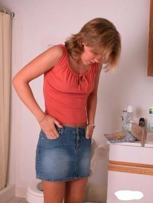 Amateur girl Karen hikes her denim skirt in the bathroom to expose her panties on fanspics.com