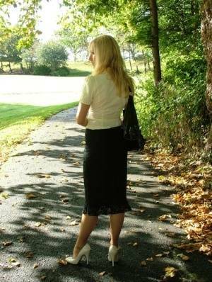 Clothed blonde Iona shows off her white stilettos in a long skirt by a park on fanspics.com