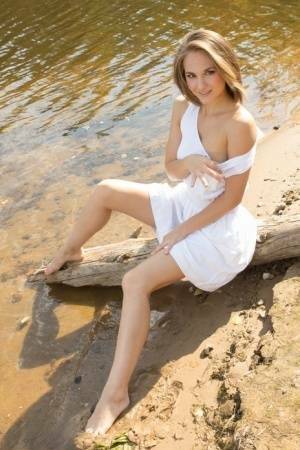 White teen of legal age shows off her naked body on a log that's beached on fanspics.com