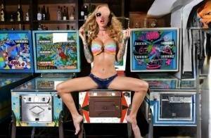 Inked chick Sarah Jessie toys her pussy atop a pinball machine while alone on fanspics.com