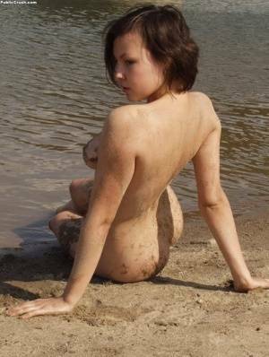 Amateur girl covers her naked body in sand while at a nude beach on fanspics.com