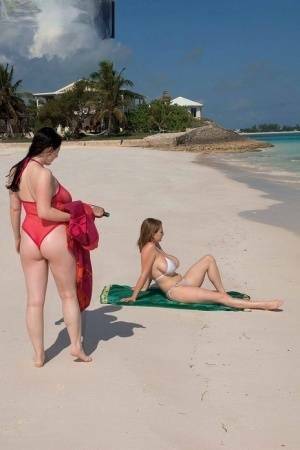 Busty lesbian girls let their huge knockers loose to kiss & lick on the beach on fanspics.com