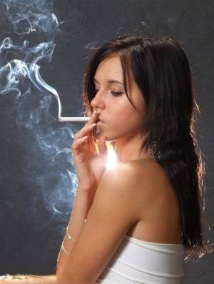 Young brunette smokes a cigarette while wrapped in tight white dress and heels on fanspics.com