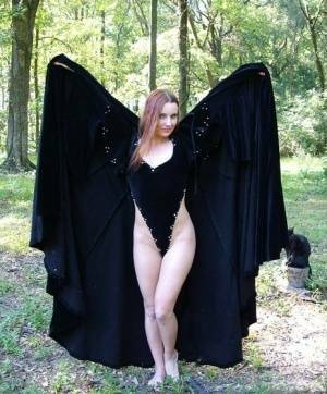 Redhead amateur Amber Lily models nude in a forest draped in a black cape on fanspics.com