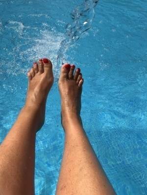 Mature woman Sweet Susi dips her painted toenails into a swimming pool on fanspics.com