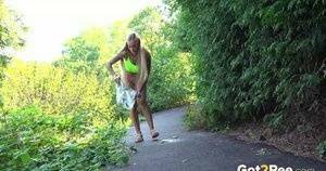 Blonde teen Daisy Lee takes a piss on a paved path through the woods on fanspics.com