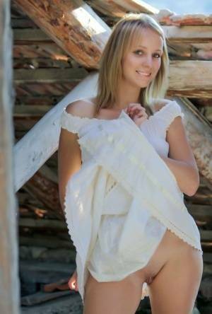 Young blonde Ilona D gets naked in a rustic setting with her boots on on fanspics.com