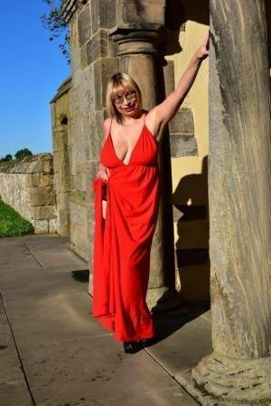 Older blonde Barby Slut doffs a red evening gown to pose nude in hosiery on fanspics.com