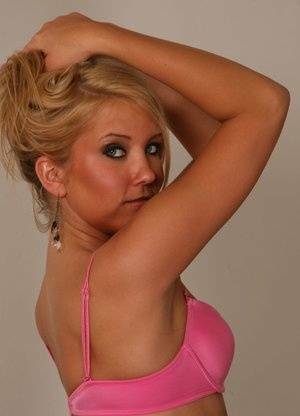 Blonde amateur Jocalynn piles up her hair before getting naked on a bed on fanspics.com