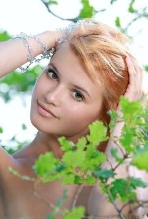 Adorable redhead Violla A displays her naked teen body atop a rock outdoors on fanspics.com